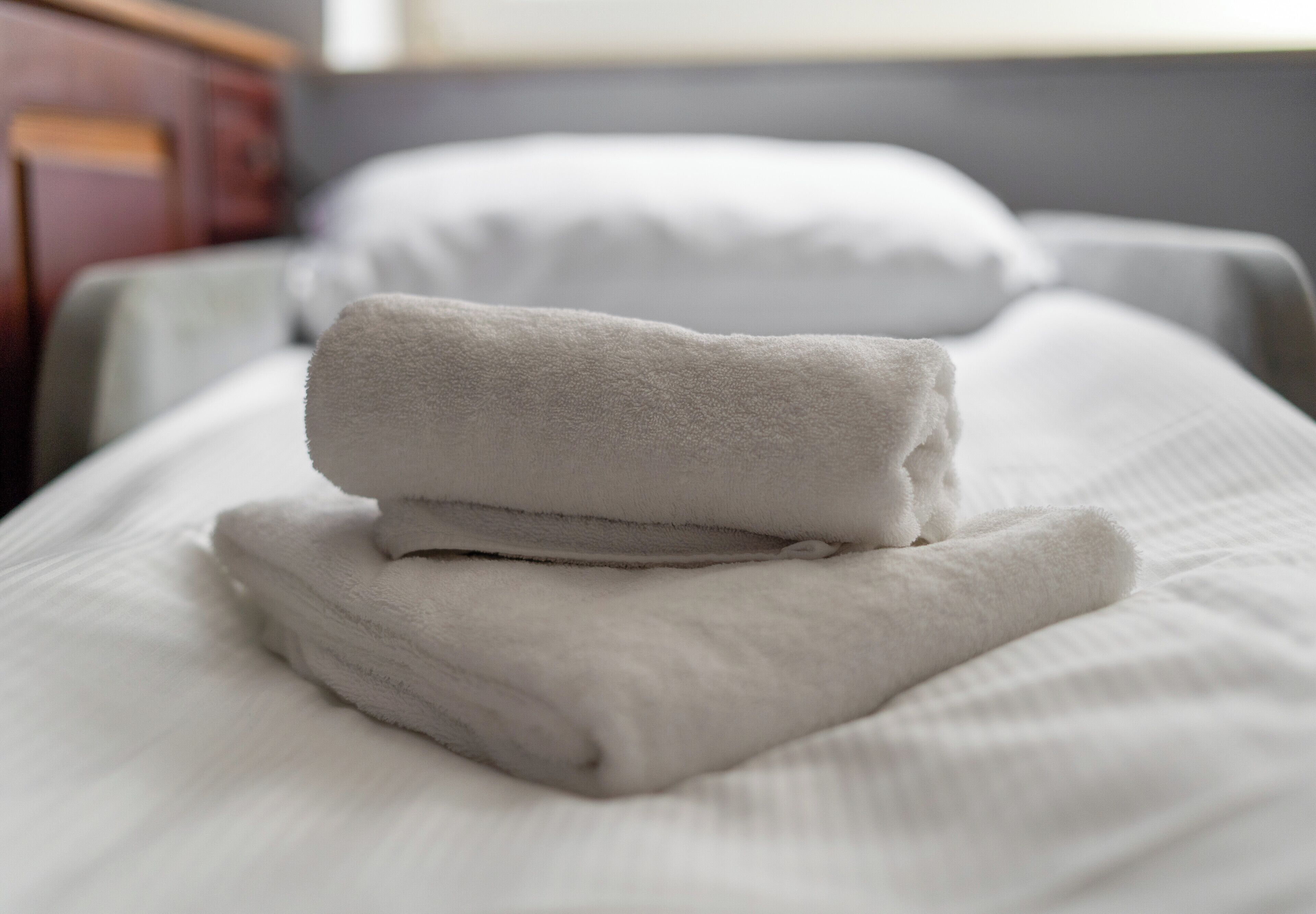 A neatly made bed with white linens and pillows.