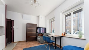 A modern room with a bed, a desk, a TV, and a window with a view of buildings. - Gliwice Comfort Stay Studio (Gliwice)