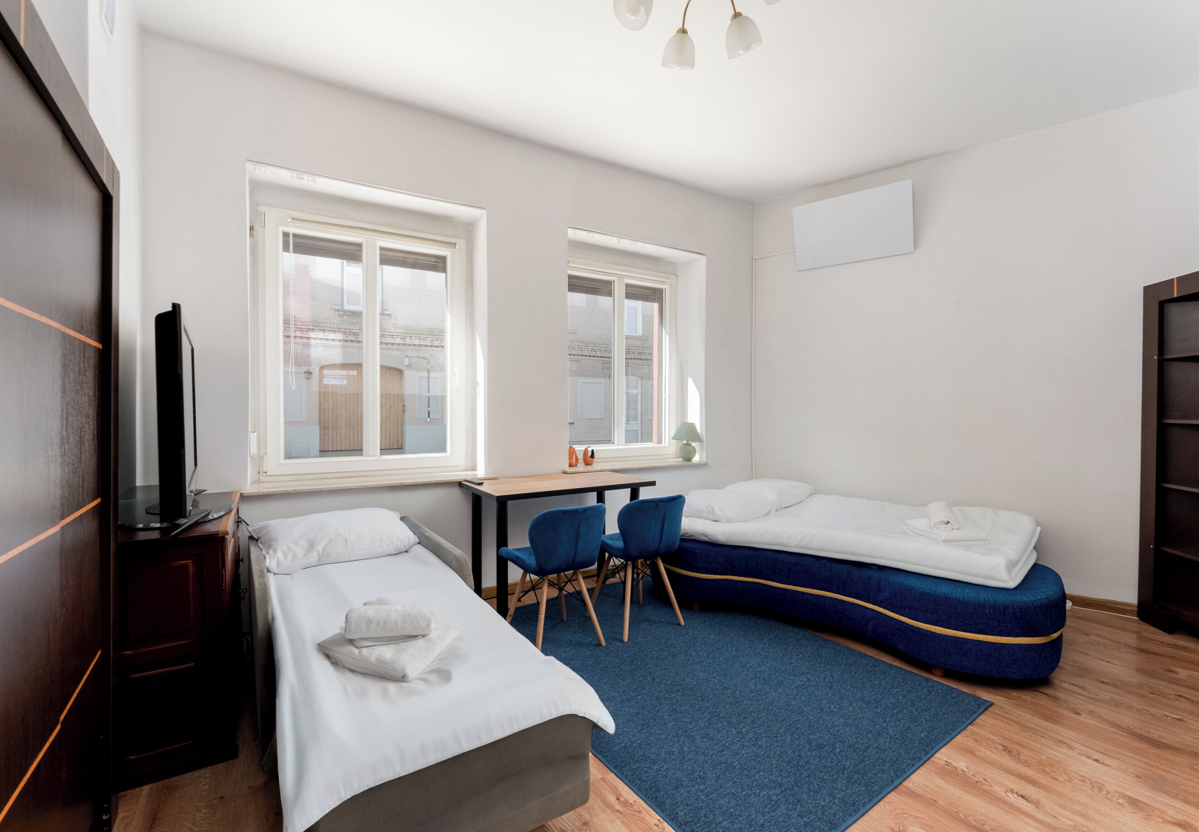Una habitación con dos camas, un escritorio, sillas y una televisión.