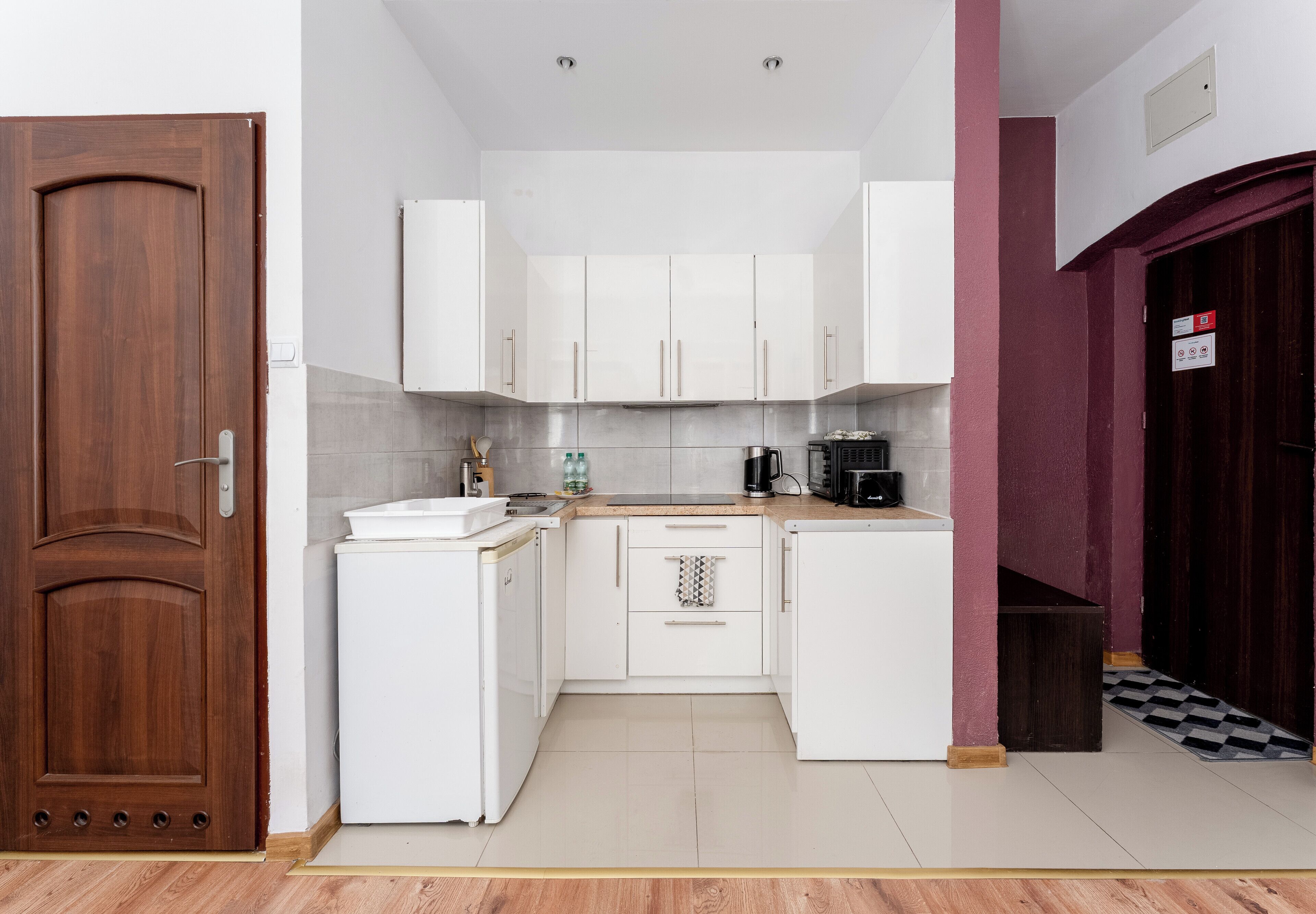 Una cocina compacta con armarios blancos, una pequeña encimera y un microondas.