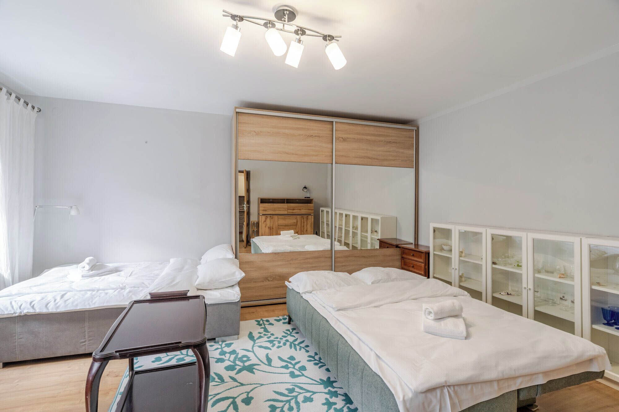 Una habitación de hotel con dos camas, un escritorio, un espejo y un armario.