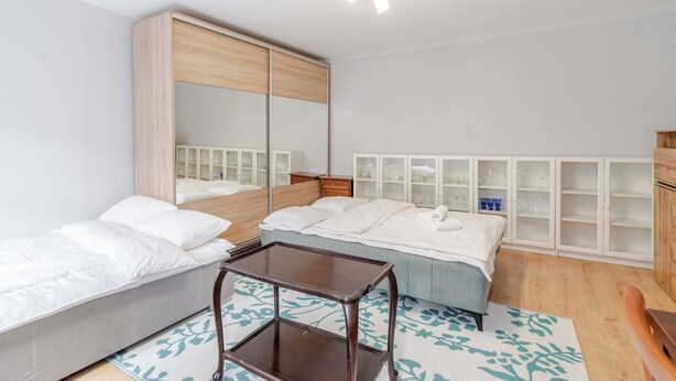 Een kamer met een bed, nachtkastje, spiegel en inbouwkasten.