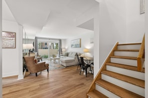 A modern living room with a sofa, coffee table, and a staircase. - Harbour Town Villa, South Beach Pool Pass, Walk to Marina & Golf Links, Warm Coastal Furnishings (Hilton Head Island)