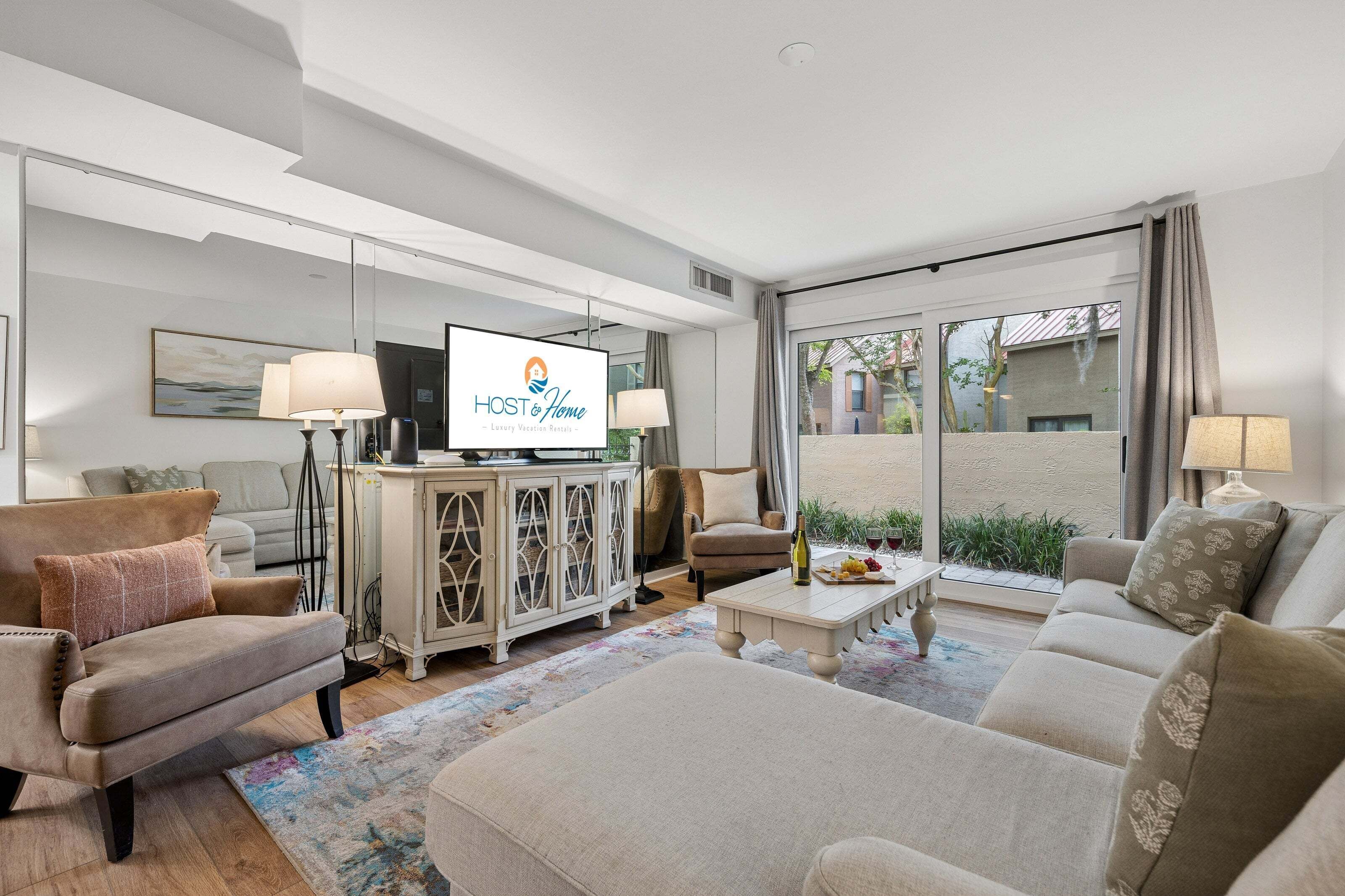 A modern living room with a television, sofas, a coffee table, and a view of the outside.