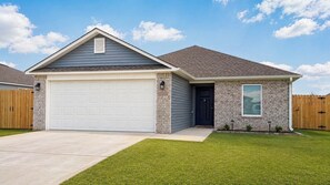 A single-story house with a garage, a small attached shed, and a well-maintained lawn.