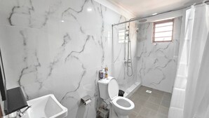 A bathroom with a marble wall, a sink, a toilet, and a shower. - Serene 2-bedroom Apartment in Central Kisumu (Kisumu)