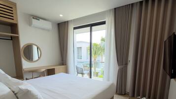 A modern bedroom with a large bed, a desk, a round mirror, and a TV.