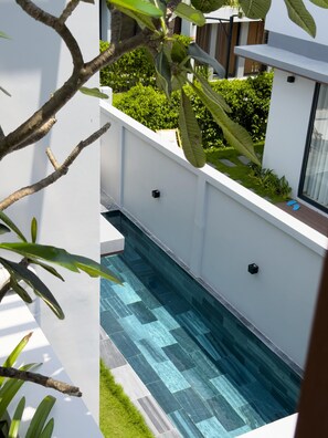 A modern outdoor pool area with a clear blue pool, white walls, and green plants. - Lagom Residence Phu Quoc (Phu Quoc)
