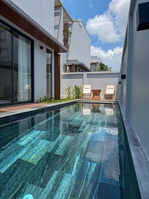 A modern swimming pool with clear water, surrounded by a white building with large windows and a wooden deck. - Lagom Residence Phu Quoc (Phu Quoc)