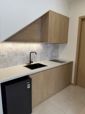 A compact kitchen with a built-in dishwasher, a sink, and wooden cabinetry. - Lagom Residence Phu Quoc (Phu Quoc)