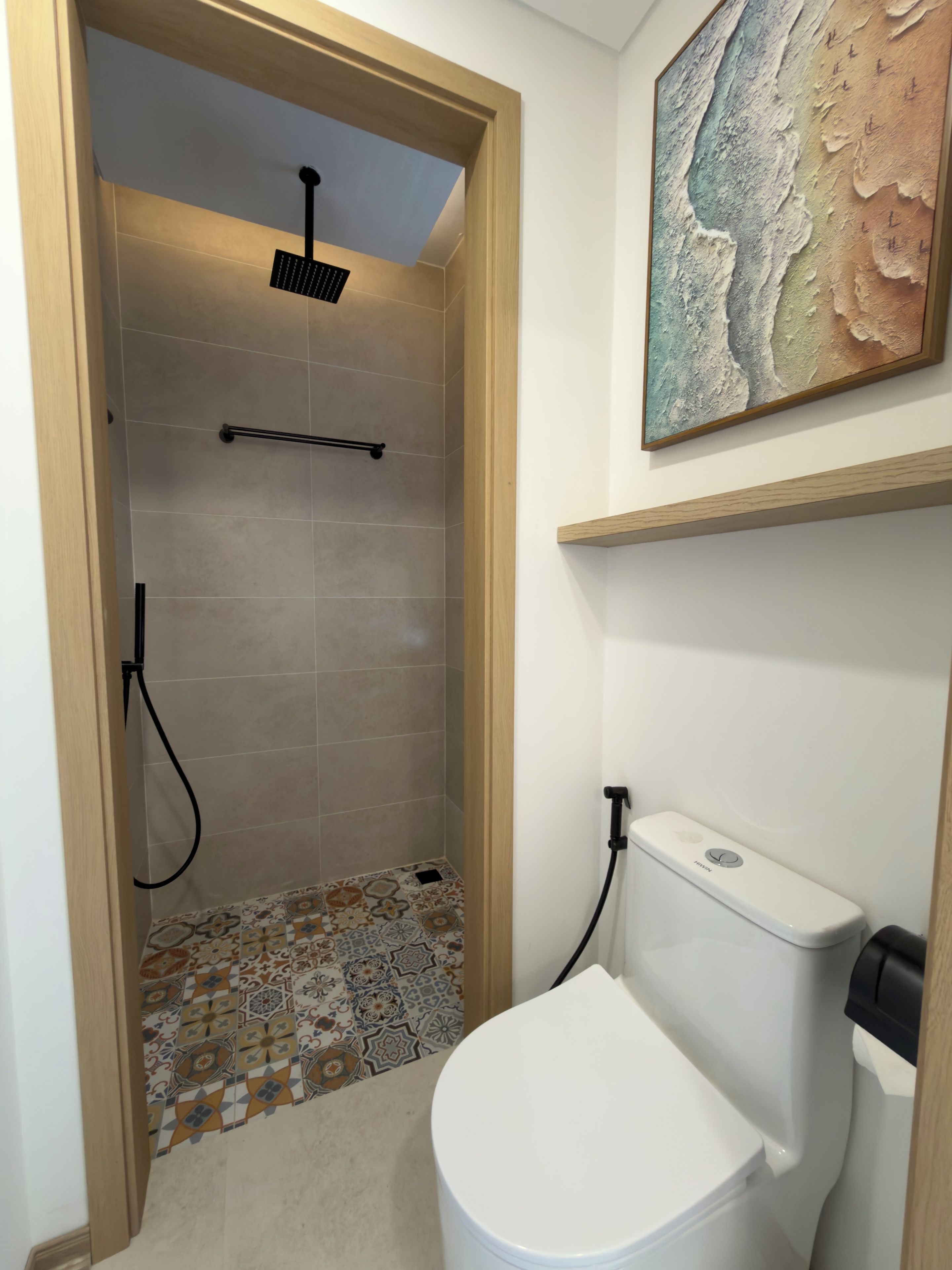 A bathroom with a shower, toilet, and a decorative tile floor.