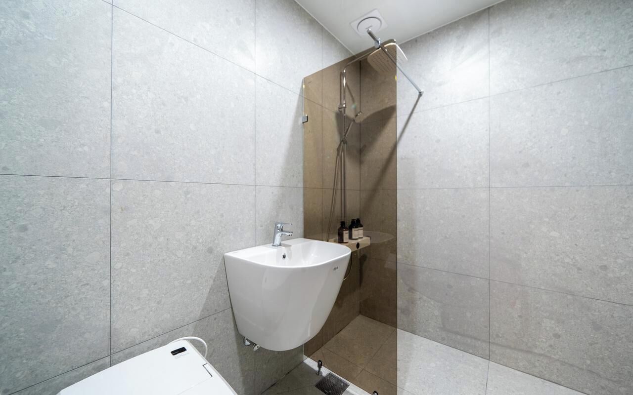 Une salle de bain moderne équipée d’une douche, d’un lavabo et de toilettes.