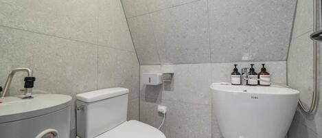 A modern bathroom with a toilet, bidet, and sink.