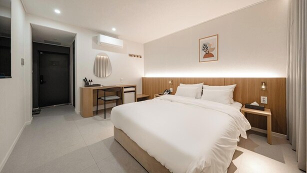 Una camera d'albergo moderna con un letto grande, comodini, una scrivania e una sedia.