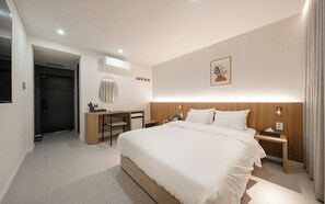 Una camera d'albergo moderna con un letto grande, comodini, una scrivania e una sedia.
