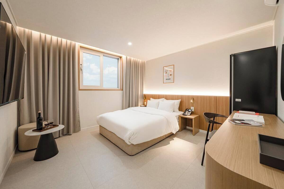 Ein Hotelzimmer mit Bett, Nachttisch, Fernseher und Schreibtisch mit Stuhl.