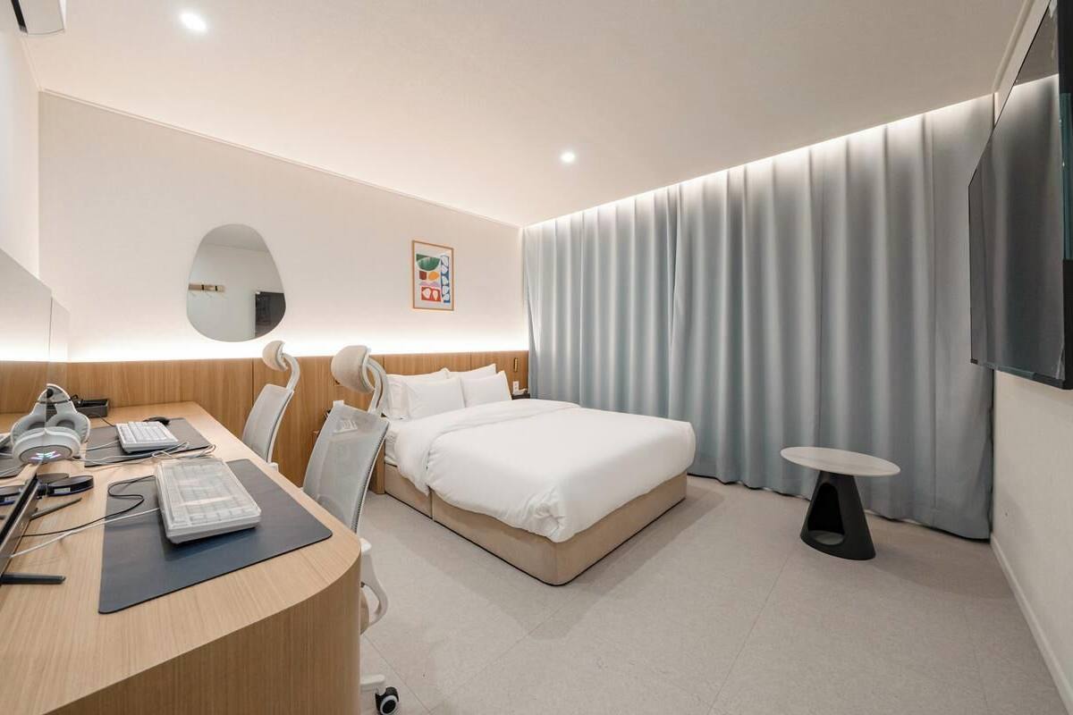 Ein modernes Hotelzimmer mit Bett, Schreibtisch, Stuhl und Fernseher.
