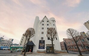 A hotel with a distinctive castle-like architecture, a grand opening banner, and a modern entrance. - Chungju H Avenue Chungju Station Branch (Chungju)