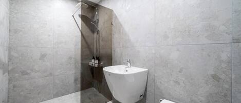 Un baño moderno con ducha de vidrio, lavamanos blanco y bañera.