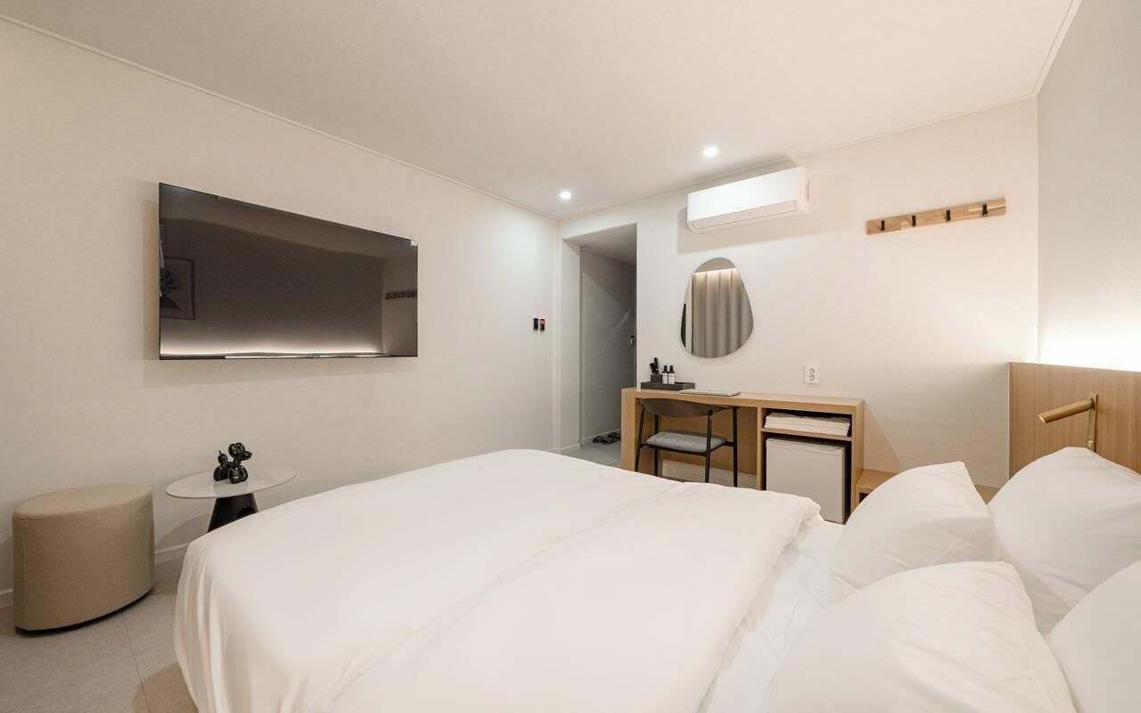 Una habitación de hotel moderna con una cama grande, un escritorio, una silla, una mesita y un espejo.