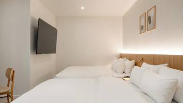 A hotel room with a large bed, a flat-screen TV mounted on the wall, and a wooden headboard.