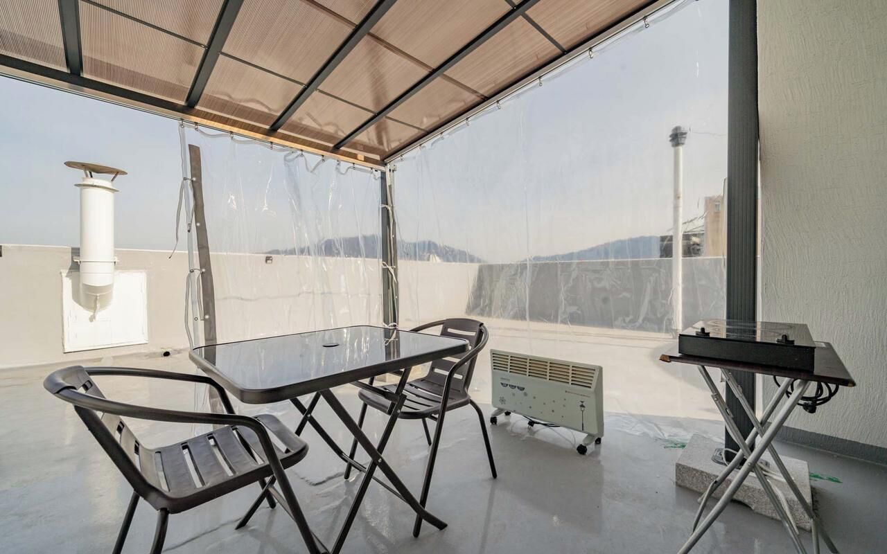 Un espacio al aire libre techado con una mesa, sillas, un radiador y un enchufe.