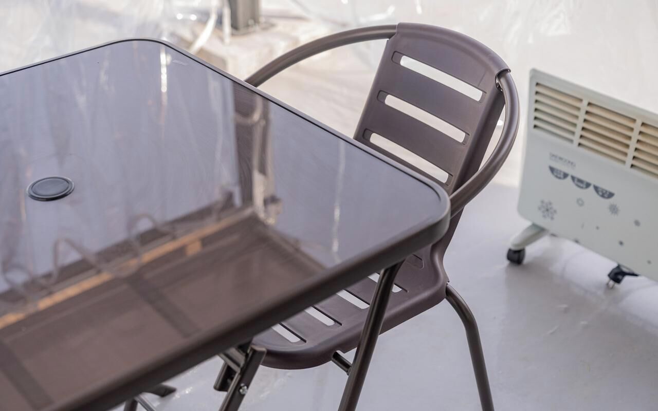 A modern, minimalist room with a glass table and a metal chair.