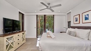 A bedroom with a bed, a television, a ceiling fan, and a balcony with glass doors. - Temple 3 Bedroom 214 (Palm Cove)