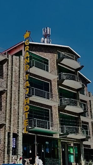 Un hôtel à plusieurs étages, doté d’une enseigne verticale bien visible, de balcons et surplombant un ciel dégagé.
