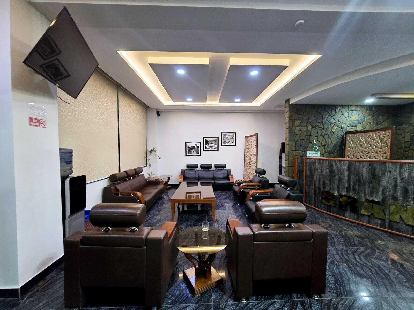 Eine Hotelhalle mit Ledersofas, einem Empfangstresen, einem Wasserspender und einem Empfangsbereich mit Steinwand.