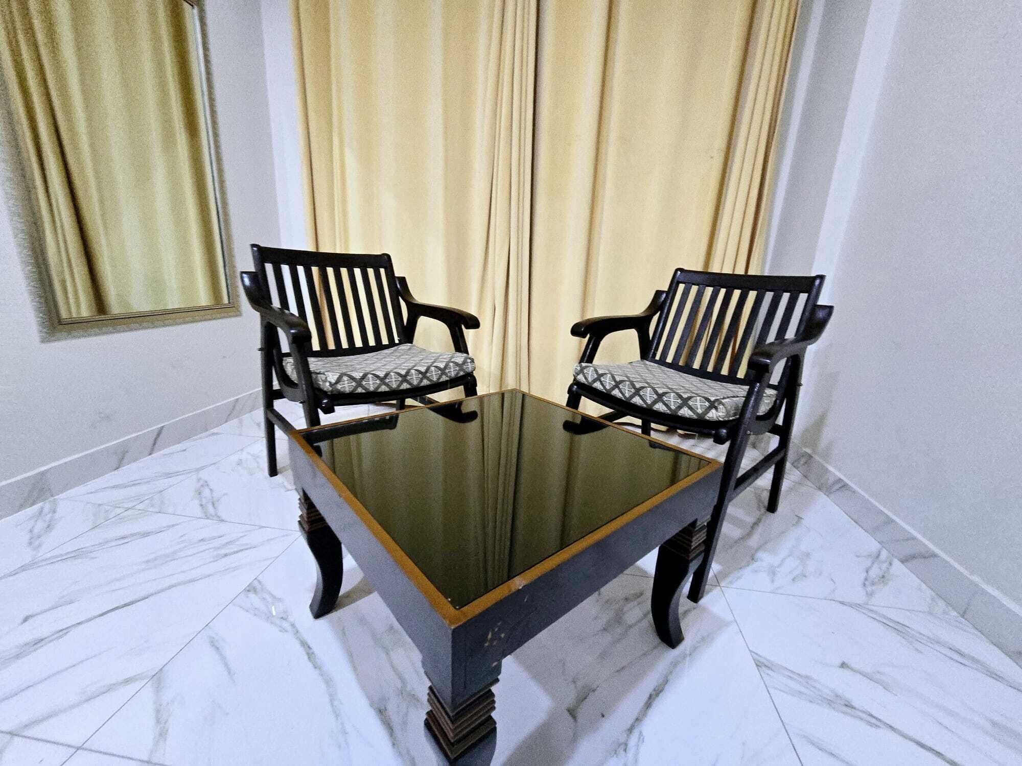 Una habitación con una mesa de vidrio y dos sillas con cojines estampados.