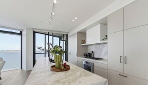 Cocina moderna con una isla grande, vista al mar y un comedor con una silla.
