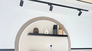Ett modernt vardagsrum med en platt-TV som är monterad på en svart TV-möbel, en vit vägg med en inbyggd hylla och en luftkonditioneringsanläggning som är monterad i taket.