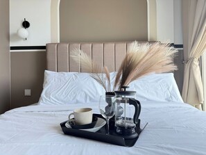 A neatly made bed with a tray containing a cup, a glass, and a coffee maker, accompanied by pampas grass. - Luxury 4Pax Studio | Bathtub | Foosball | Parking (Kuala Lumpur)