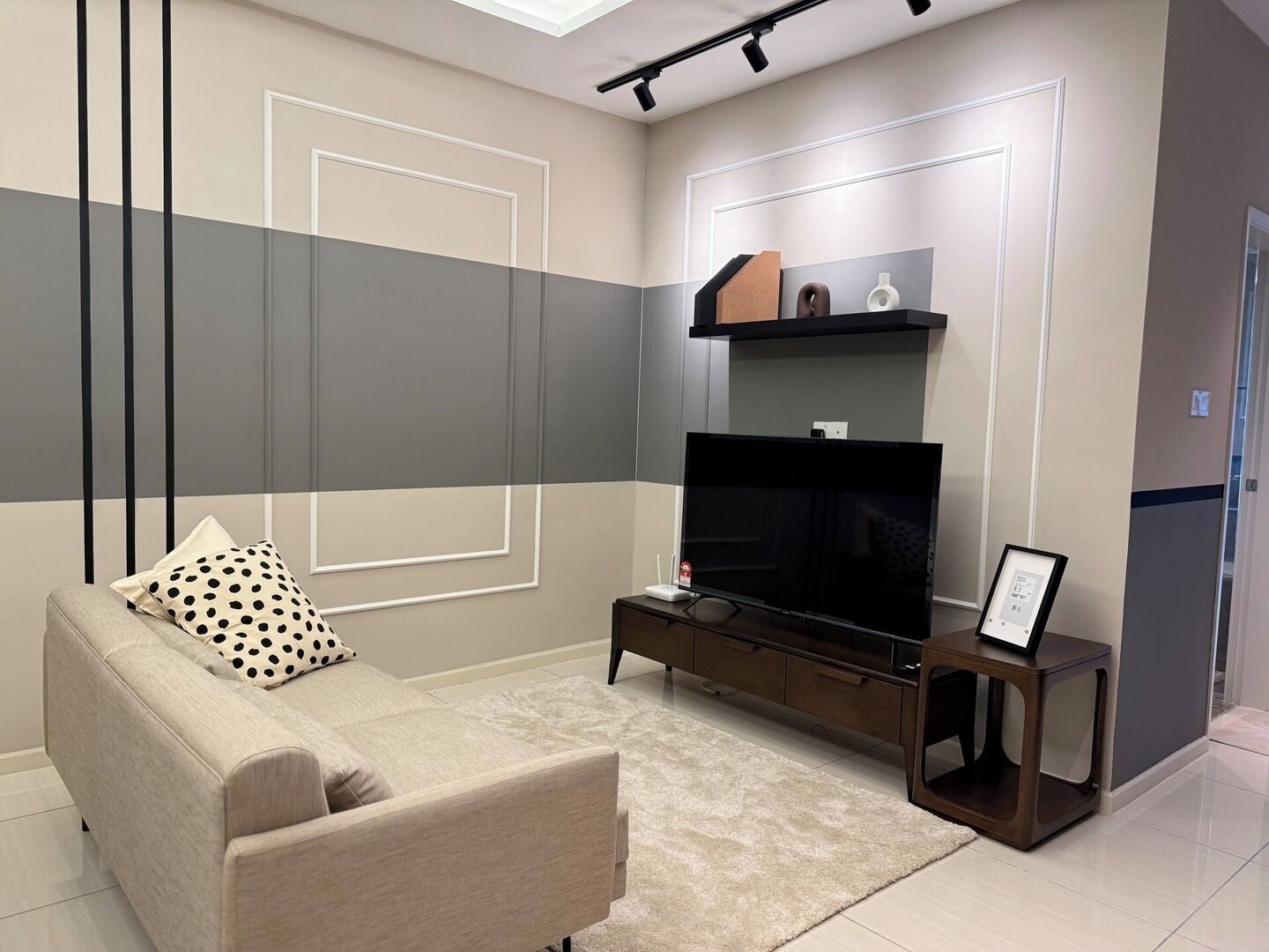 Un salon moderne avec un canapé, un téléviseur et une petite table basse.
