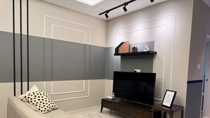 A modern living room with a sofa, TV, and a small coffee table. - Calming Blue Studio 3Pax | Bathtub | Parking (Kuala Lumpur)