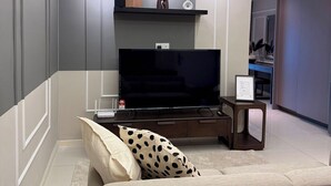 A modern living room with a flat-screen TV, a sofa, a coffee table, and a side table with a picture frame. - Calming Blue Studio 3Pax | Bathtub | Parking (Kuala Lumpur)