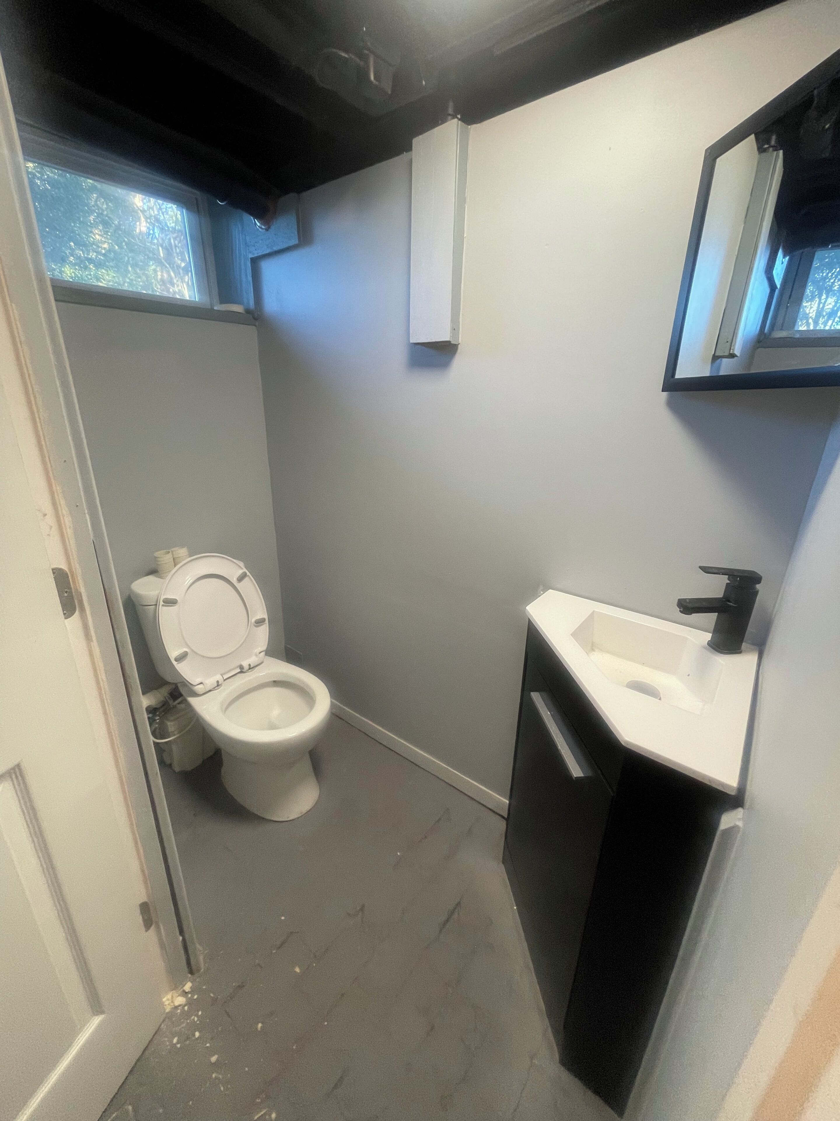 A small bathroom with a toilet, sink, and mirror.