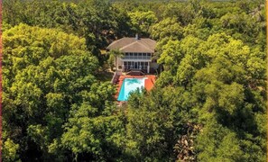A house surrounded by dense trees with a swimming pool in front. - Spacious, historic 6-bedroom house in peaceful Fruitland Park with AC (Fruitland Park)