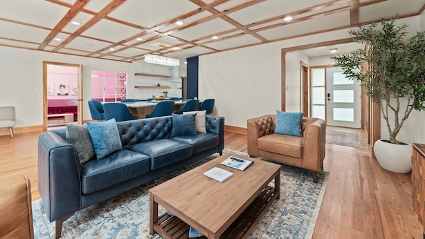 Ein modernes Wohnzimmer mit einer Ledersofa, einem Holztisch und einer großen Kübelpflanze.