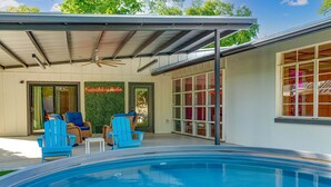 Ein Poolbereich mit blauen Stühlen, einem Deckenventilator und einer grünen Wand.