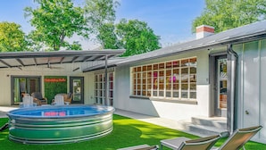 Ein modernes Haus mit Schwimmbad, Sitzgelegenheit im Freien und einem großen Fenster.