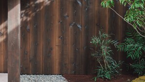 A wooden fence with a gravel path and a small plant. - MUDANI DARUMACHO (Kyoto)