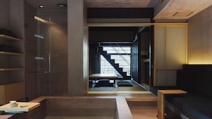 A modern interior with a glass-enclosed bathroom, a seating area with a table and chairs, and a sofa. - MUDANI DARUMACHO (Kyoto)