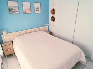 Ein Schlafzimmer mit einem Bett, einem Nachttisch, einer Kommode und einer Wand mit drei gerahmten Bildern.