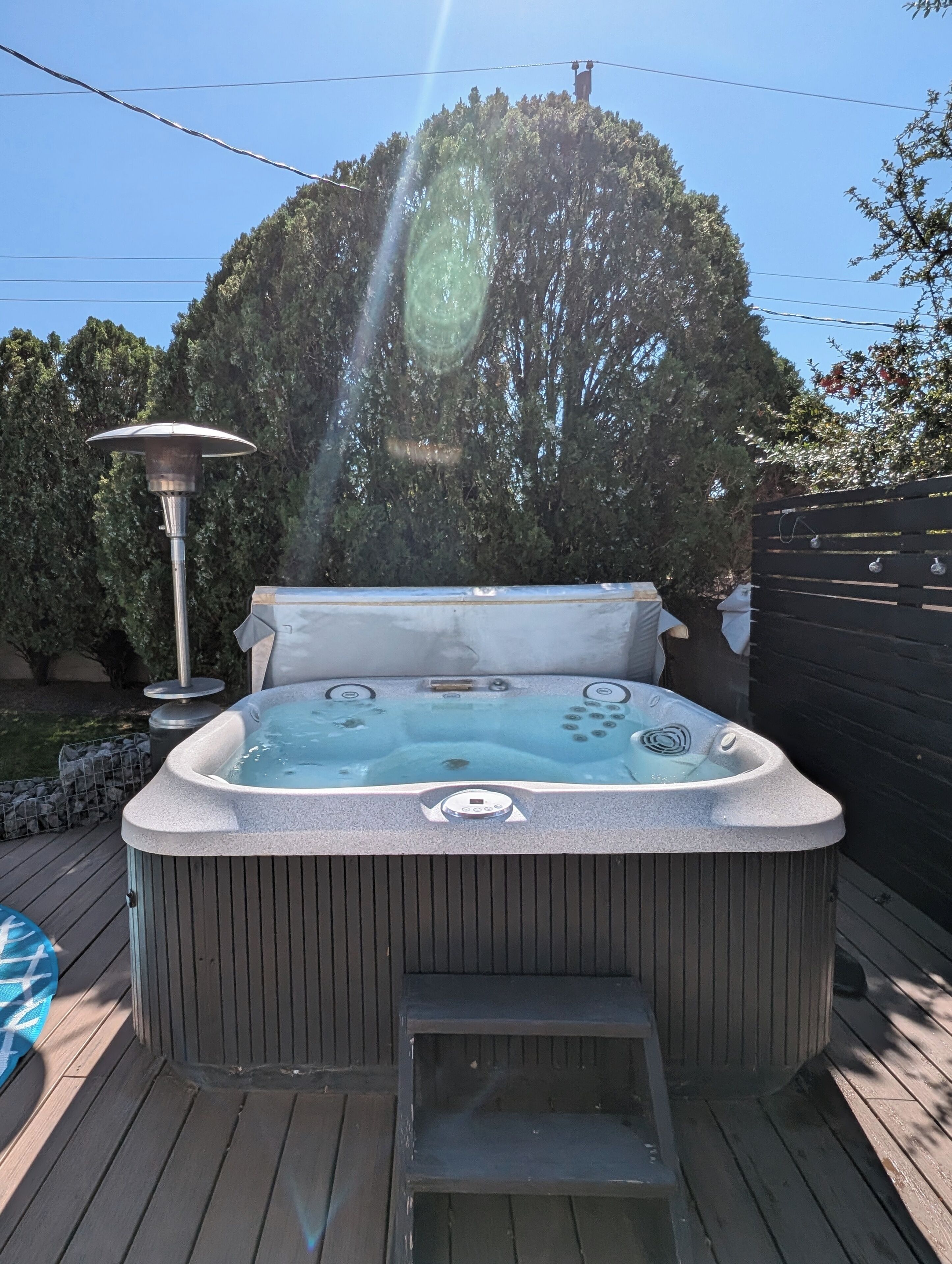 Un bain à remous doté d’un panneau de commande, entouré d’une terrasse en bois et d’un chauffage en métal.