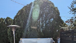 Ein Whirlpool mit Bedienfeld, umgeben von einer Holzterrasse und einem Metall-Heizgerät.