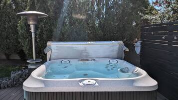 Un bain à remous doté d’un panneau de commande, entouré d’une terrasse en bois et d’un chauffage en métal.
