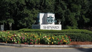 Un letrero con la palabra 'SHIPYARD', rodeado por un cantero con diversas flores.