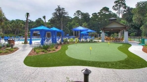 Un campo de golf con un putting green, tiendas azules y un pabellón.
